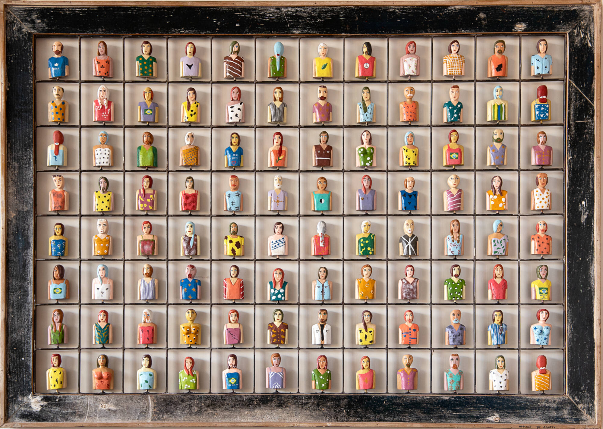 Wooden structure with lots of small people shaped carvings in their own little cubby. Each person is painted in bright colors with different patterns.